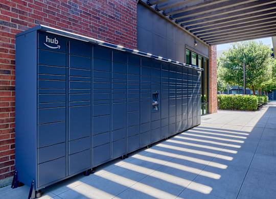A large dark blue Amazon storage unit is on a sidewalk.