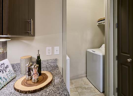 A kitchen counter with a wooden plate on it and a bottle of wine.