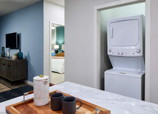 A tray with two coffee mugs and a white container sits on a marble countertop.