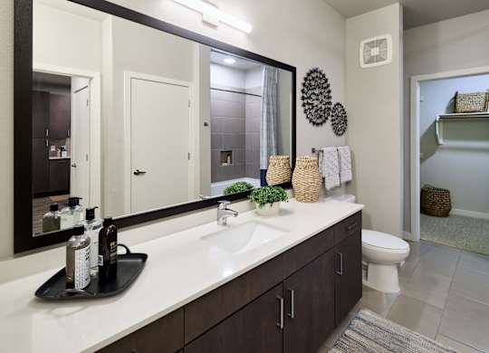 A bathroom with a white counter top and a large mirror.