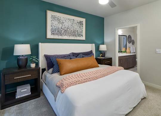 A bedroom with a bed, nightstands, and a painting on the wall.