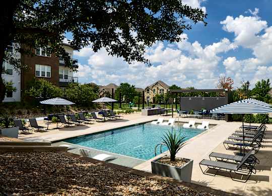 A pool surrounded by lounge chairs and umbrellas.