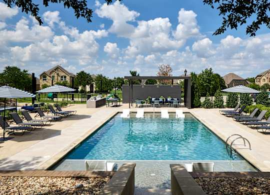 A large swimming pool surrounded by lounge chairs and umbrellas.