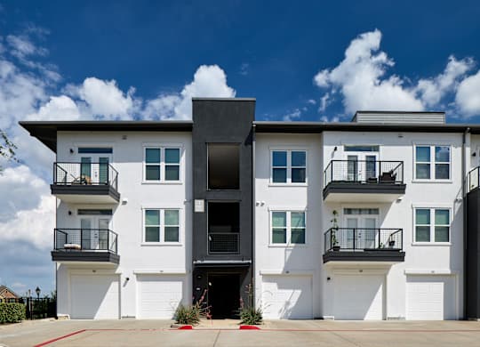 A modern two-story building with white walls and black balconies.