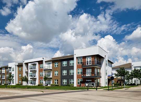 A large apartment complex with a parking lot in front.