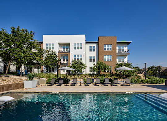 A modern apartment complex with a swimming pool in the foreground.