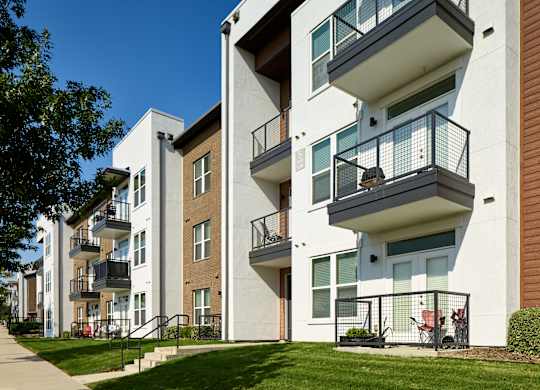 Apartment building with balconies and green lawn in front.