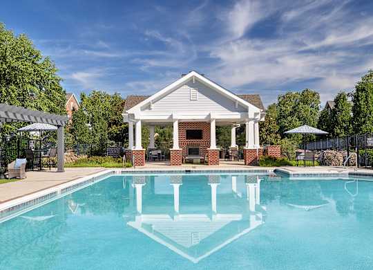 A pool in front of a house with a white roof.