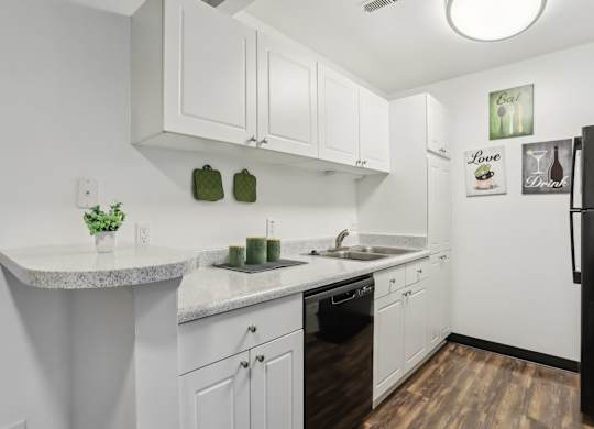 A kitchen with white cabinets and a black refrigerator. at Millennium at Creve Coeur, Missouri