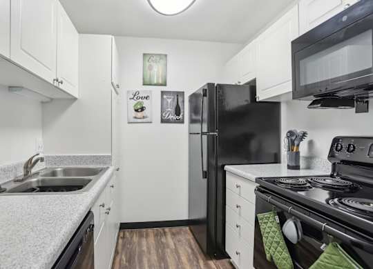 A black refrigerator sits in a kitchen with white cabinets. at Millennium at Creve Coeur, Missouri