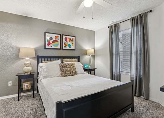 A bedroom with a large bed, two lamps, and a painting on the wall.