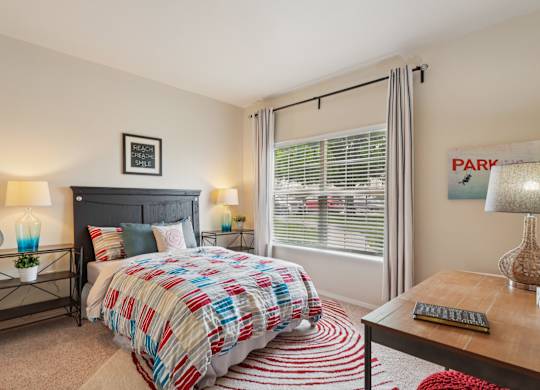 A bedroom with a bed, nightstand, and window.