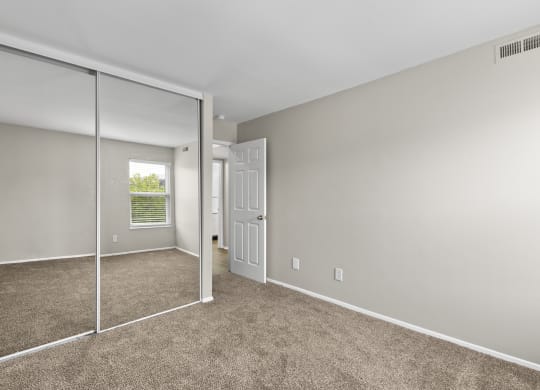 Bedroom with a mirrored closet and carpeted floors at Creve Coeur, Creve Coeur, MO