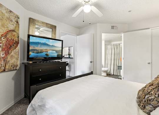 A bedroom with a bed, dresser, and a painting on the wall.