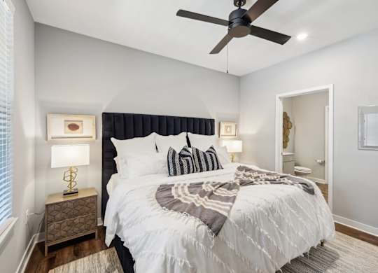 A bedroom with a large bed and a ceiling fan.