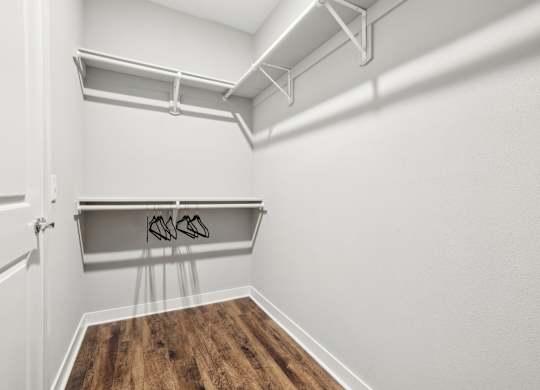 A white closet with a wooden floor and a white door.