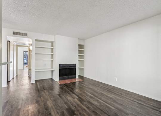 A room with a fireplace and wood flooring.