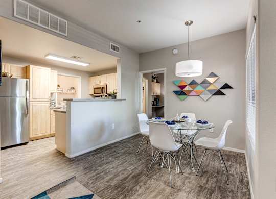 A modern kitchen with a dining table set for four at Sweetwater At Metro North Apartments, Arizona 85029
