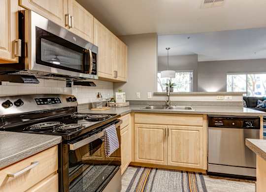 A kitchen with wooden cabinets and stainless steel appliances at Sweetwater At Metro North Apartments, Phoenix, Arizona