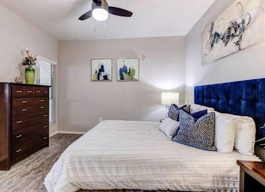 A bedroom with a bed, dresser, and two pictures on the wall at Sweetwater At Metro North Apartments, Phoenix  85029