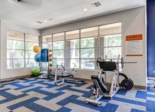 A gym with a blue and white checkered floor and exercise equipment at Sweetwater At Metro North Apartments, Arizona 85029