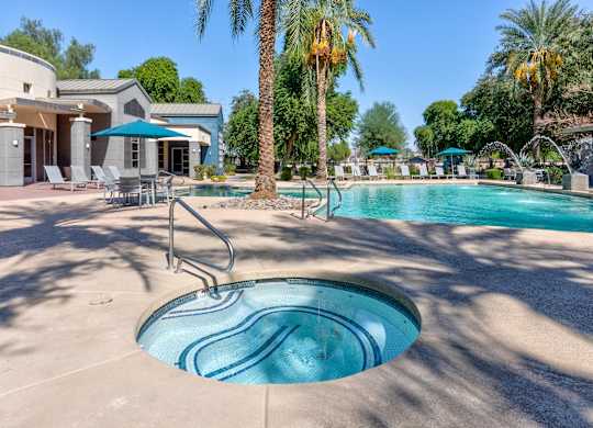 A pool with a slide and palm trees in the background at Sweetwater At Metro North Apartments, Arizona