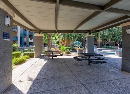 A concrete patio with a table and chairs under a roof at Sweetwater At Metro North Apartments, Phoenix