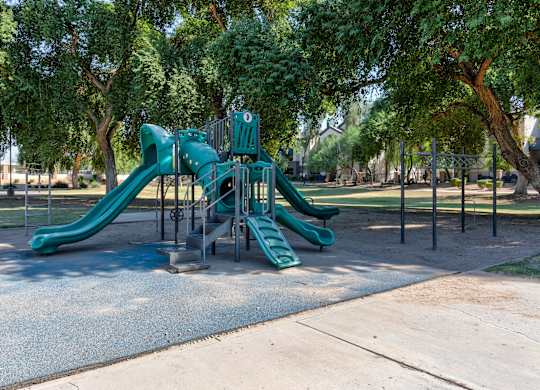 A playground with a green slide and a climbing structure at Sweetwater At Metro North Apartments, Phoenix, AZ 85029