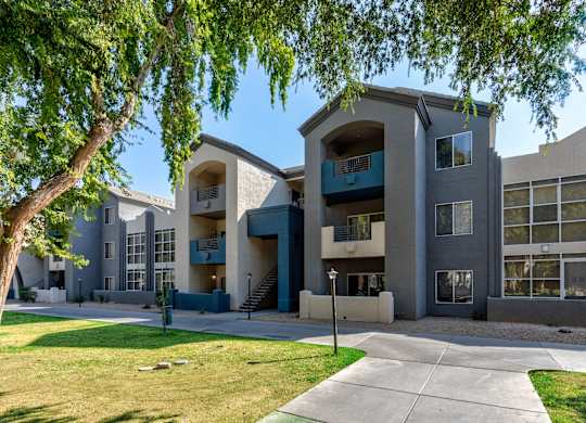 A modern apartment building with a tree in the foreground at Sweetwater At Metro North Apartments, Phoenix  85029