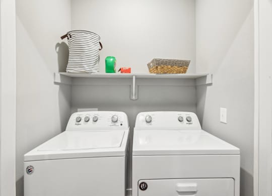 A laundry room with two washing machines and a shelf above them.