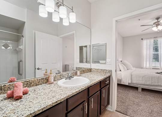 A bathroom with a sink, mirror, and bed.
