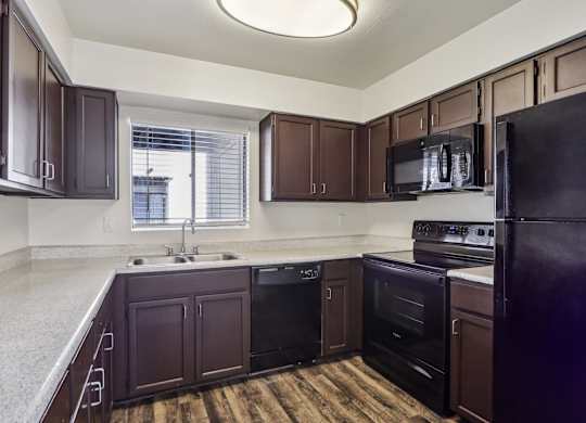 A kitchen with dark brown cabinets and black appliances.