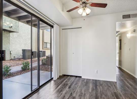 A room with a ceiling fan and sliding glass doors.