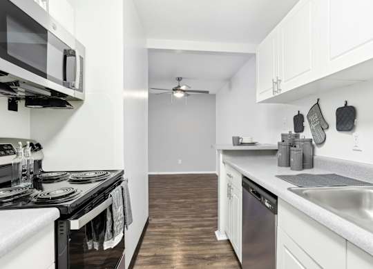 A modern kitchen with white cabinets and a black stove top.