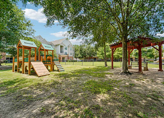 A playground with a swing set and a treehouse in a park.