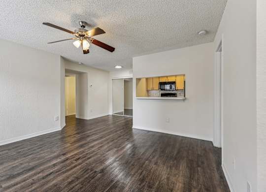 A room with a ceiling fan and wooden flooring.