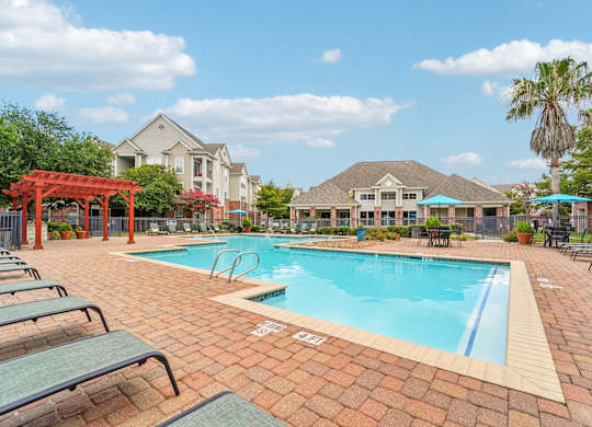 A pool surrounded by lounge chairs and umbrellas.