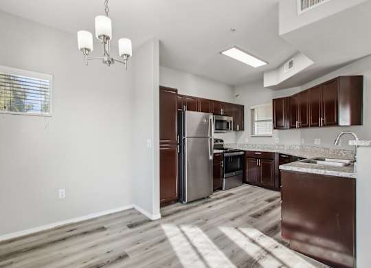 A kitchen with brown cabinets and a stainless steel refrigerator at Sweetwater At Metro North Apartments, Phoenix, Arizona