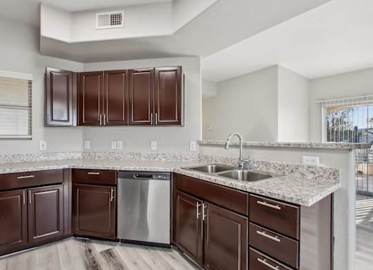 A kitchen with brown cabinets and a stainless steel dishwasher at Sweetwater At Metro North Apartments, Phoenix  85029