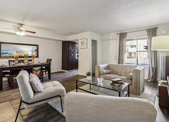 A living room with a beige couch, a glass coffee table, and a chair.