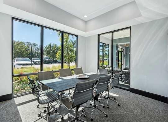 A conference room with a table and chairs and a view of the outside.