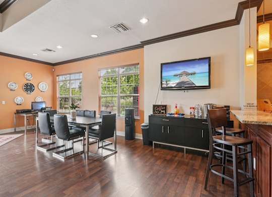 A living room with a television, chairs, and a bar area.