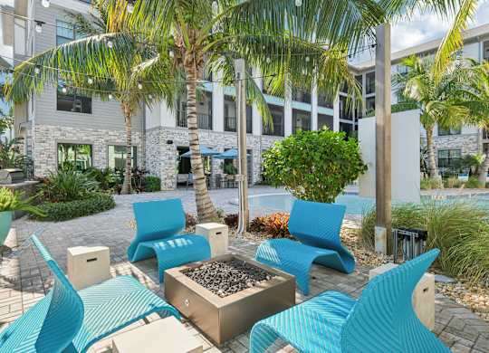 A modern outdoor seating area with blue chairs and a fire pit.