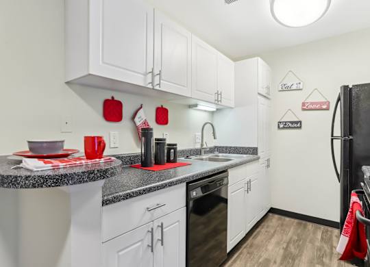 A kitchen with white cabinets and a black refrigerator. at Millennium at Creve Coeur, Creve Coeur, 63141