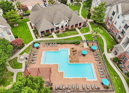 A large swimming pool surrounded by a brick wall and lounge chairs.