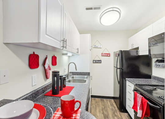 A kitchen with black appliances and red accents. at Millennium at Creve Coeur, Creve Coeur, 63141