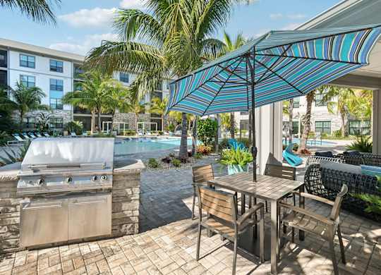 A patio with a table and chairs and a grill.