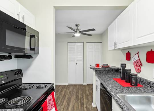 A kitchen with a black stove top oven and a black microwave above it. at Millennium at Creve Coeur, Creve Coeur, 63141