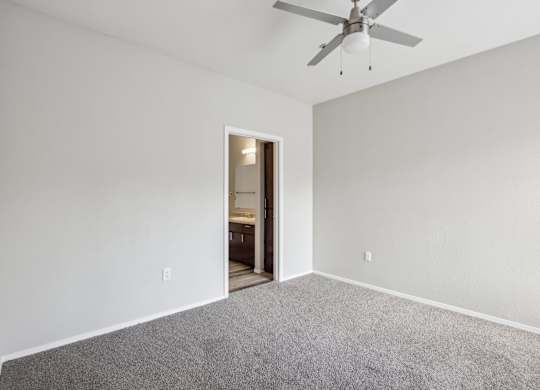 A room with a ceiling fan and carpeted floor at Sweetwater At Metro North Apartments, Arizona