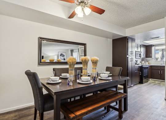A dining room with a table set for two and a bench.